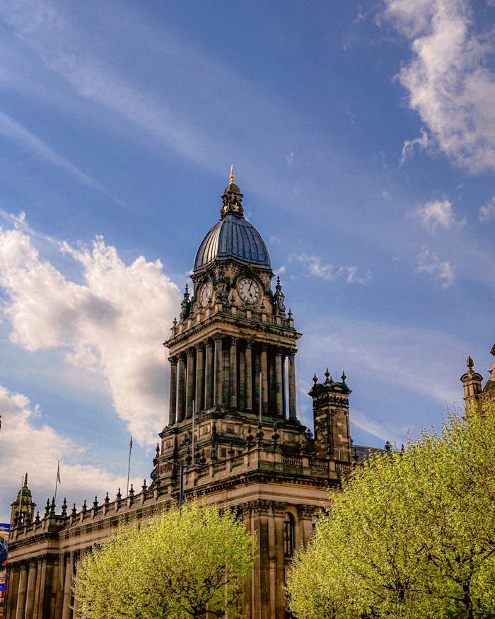 Stunning view of Leeds Town Hall with lush green trees and a clear blue sky.